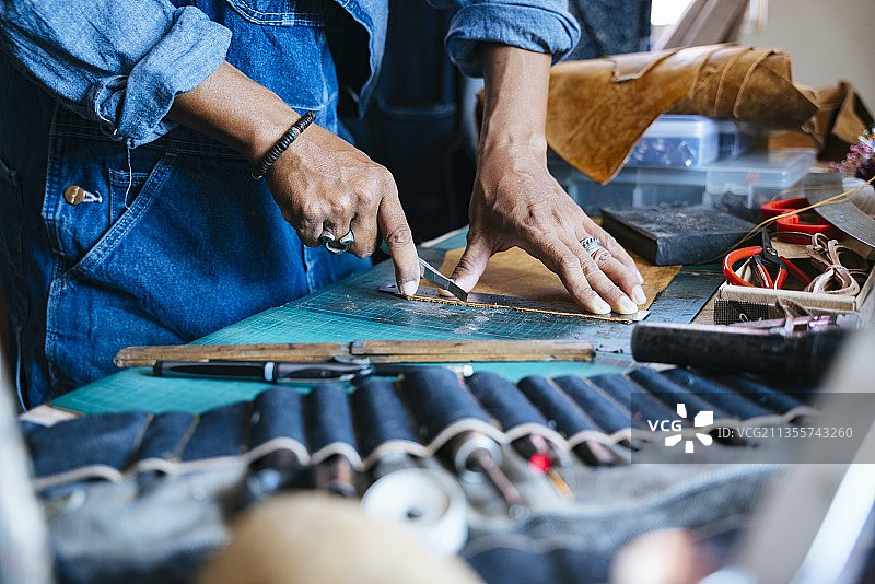 靛蓝商店的工匠在切割时，切割席上的皮革穿过了设备。图片素材