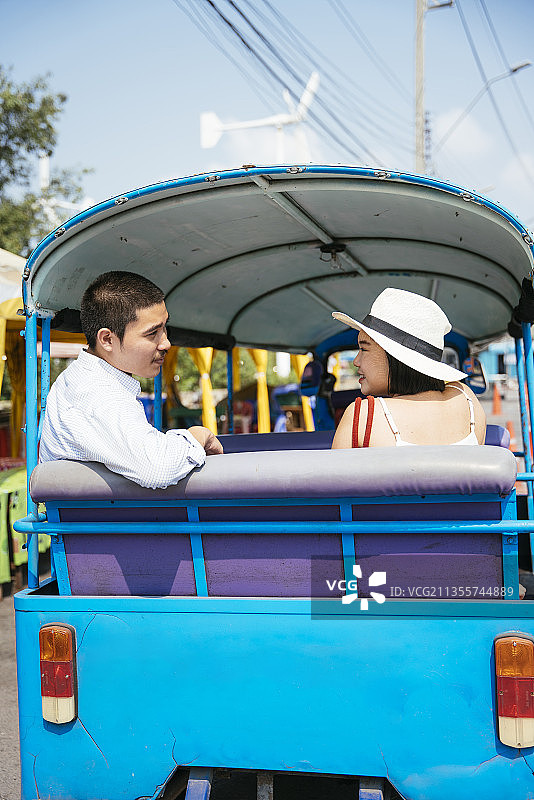 后视图-亚洲的泰国夫妇乘坐嘟嘟车在曼谷旅行。垂直拍摄。图片素材