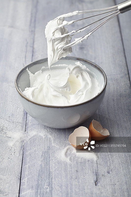 碗中和搅拌器上的打发蛋白（蛋白酥皮）图片素材