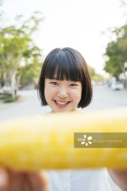 近距离拍摄亚洲女子波波头在户外吃煮玉米。健康的水果和蔬菜图片素材