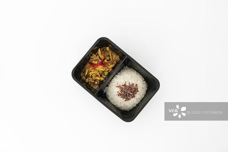 顶视图的辣咖喱猪肉与米饭在一边，黑色的包装箱隔离在白色。图片素材