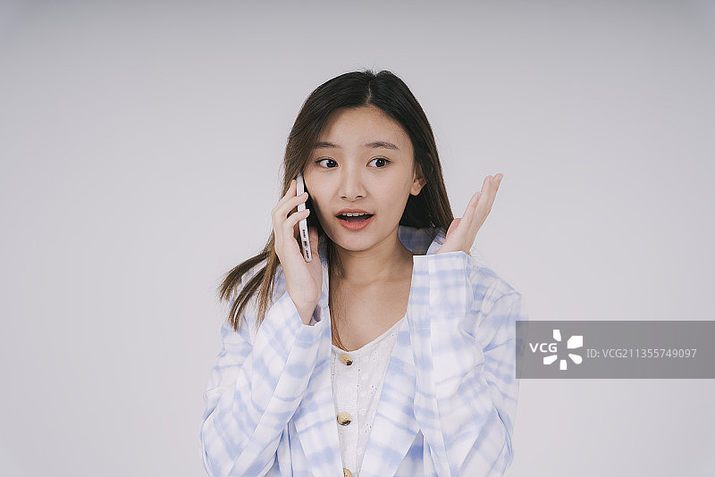 美丽的泰国女商人感到惊人的谈话在电话隔离在白色的背景。图片素材