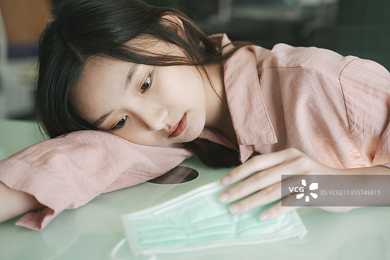 病人漂亮的亚洲女人戴着医生口罩和粉红色衬衫躺在桌子上等待医生在医院。图片素材