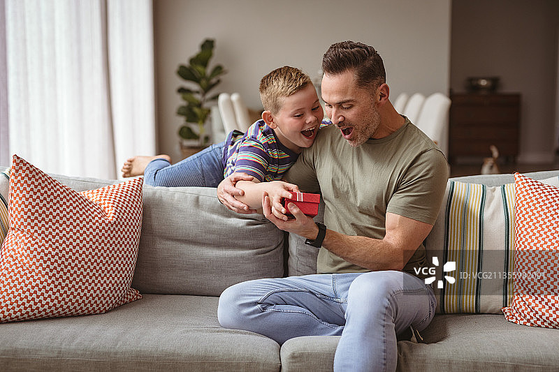 圣诞节期间，白人男孩在家给父亲送圣诞礼物图片素材