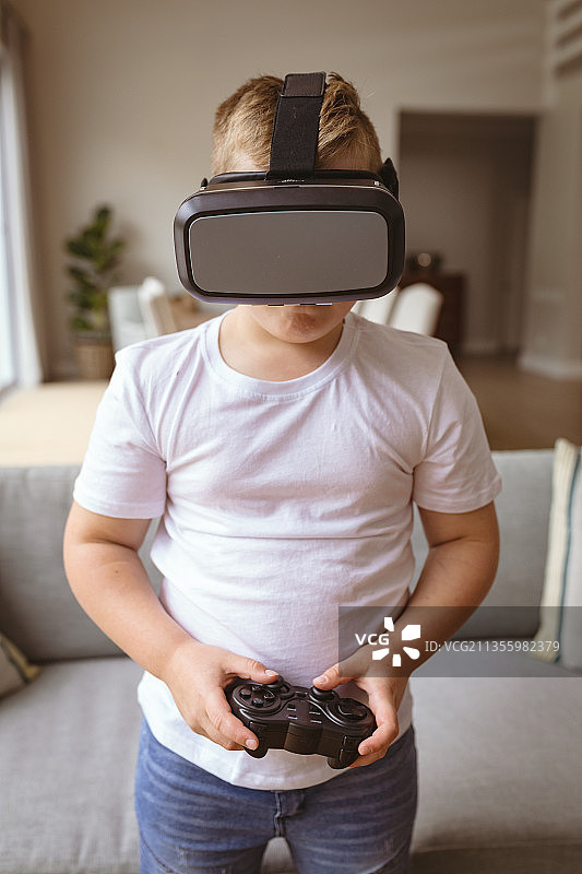 戴VR眼镜在家玩游戏的白人男孩图片素材