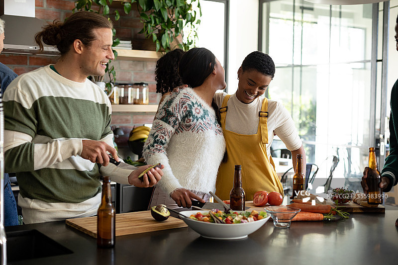 一群快乐的男女友人在厨房里喝啤酒烹饪图片素材