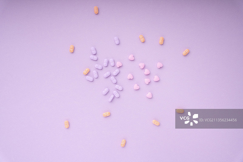 俯视图-粉彩维生素药物在紫色粉红色的背景。混乱和分离。图片素材