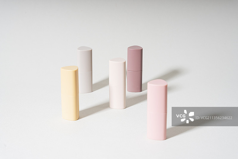 米色和粉色的背景上有很多不同的唇膏。美丽的图案和概念，化妆品，女性配件。口红管的颜色。图片素材