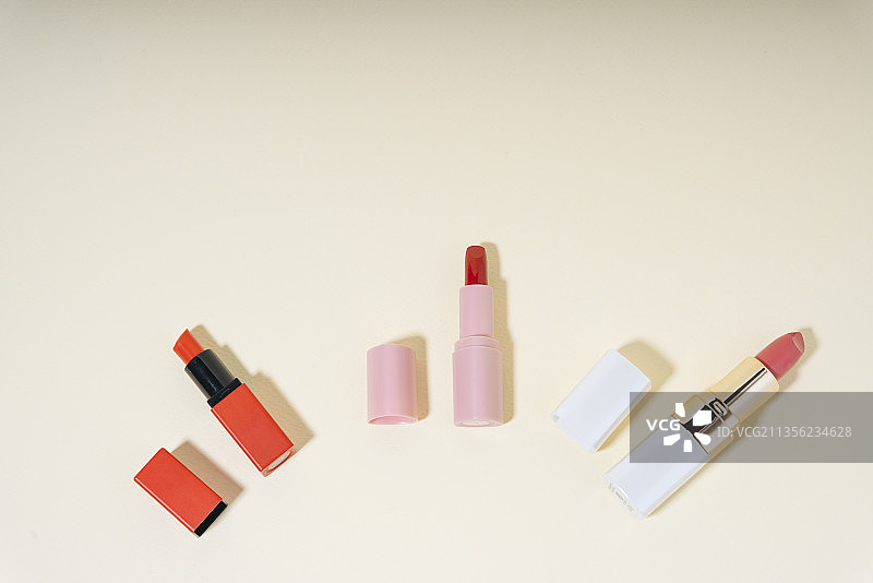在美丽的背景上，红色和橙色唇膏的特写俯视图。图片素材