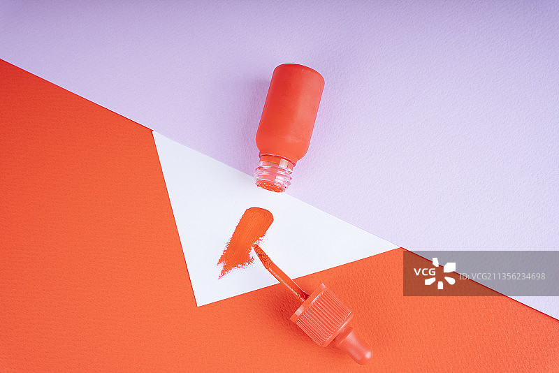 化妆唇刷和红色液体唇膏的瓶子特写彩色背景与copyspace。图片素材