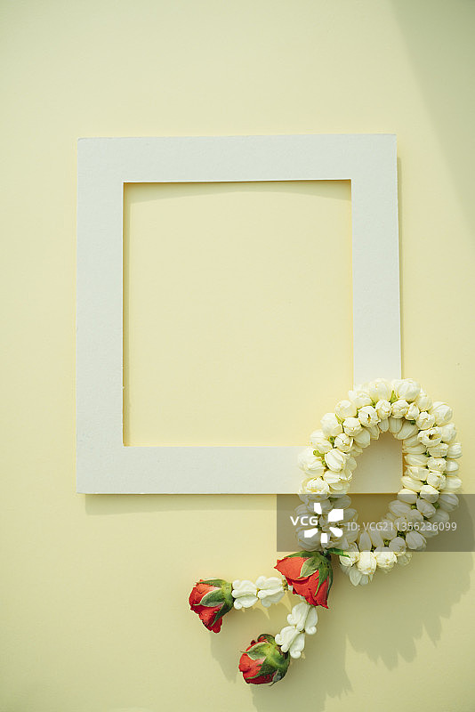 泰国花花环茉莉花和玫瑰与模拟白色框架在明亮的黄色背景。前视图。图片素材