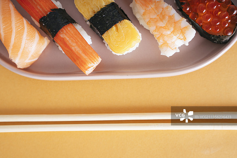 头顶拍摄的日本寿司放在用筷子夹着的盘子上。图片素材