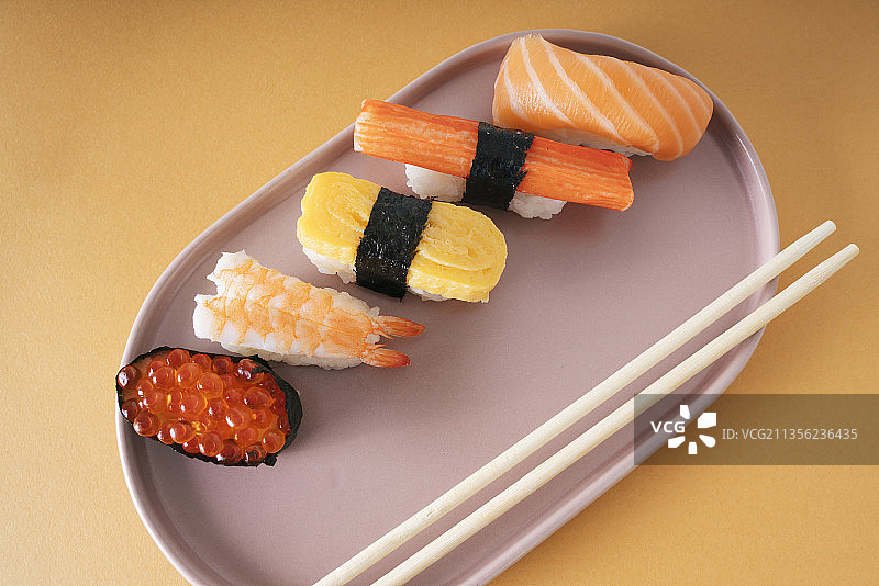 头顶拍摄的日本寿司放在用筷子夹着的盘子上。图片素材
