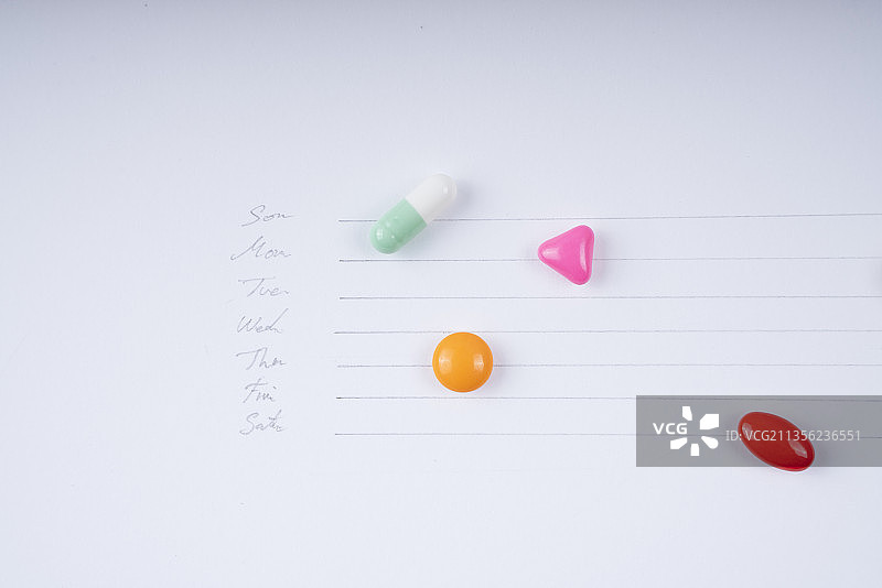 每日服用药片-彩色药片在白色背景上的时间表。图片素材