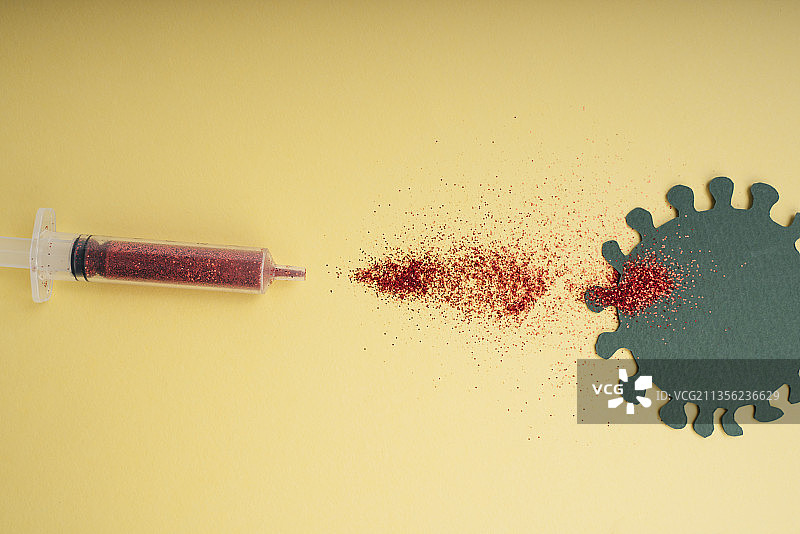 疫苗从注射器中流出，在黄色背景上流出病毒。图片素材