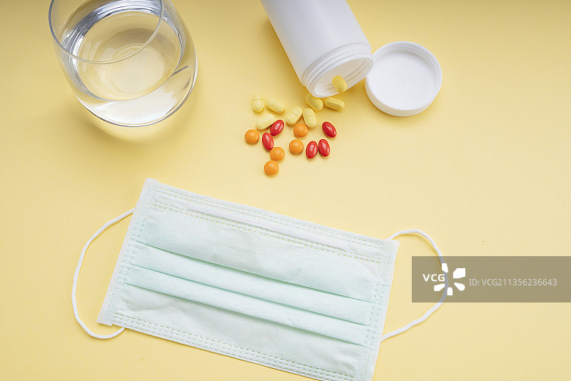 俯视图-医生面具和水杯与药丸从白色瓶子盒子。图片素材