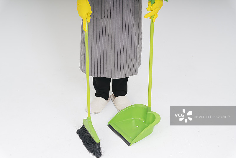 女佣用扫帚和簸箕清洁地板。图片素材