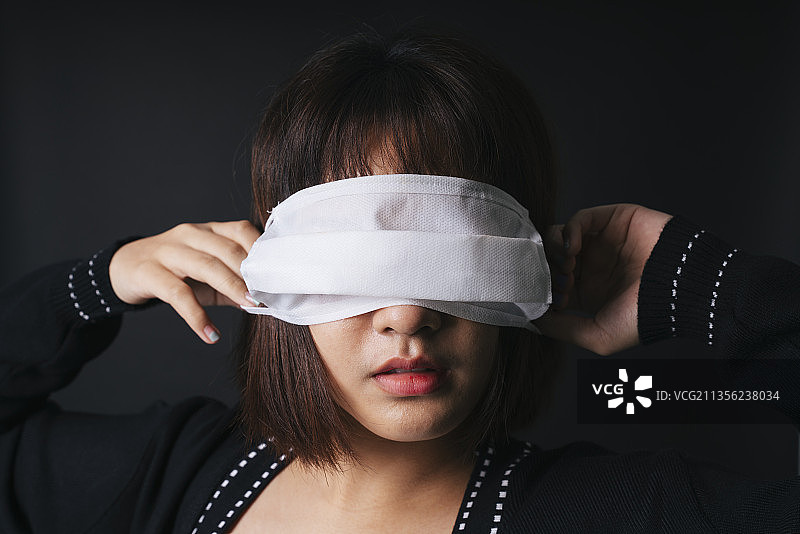 美丽的亚洲泰国女人短发盖eY面具。隔离在黑色背景上。特写肖像。图片素材