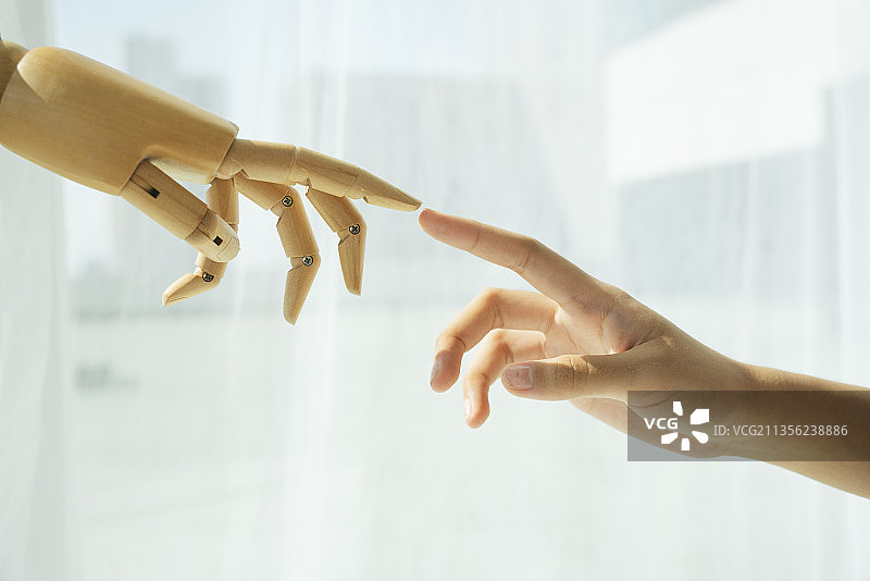 木制机器人的手和人的手相互接触。图片素材