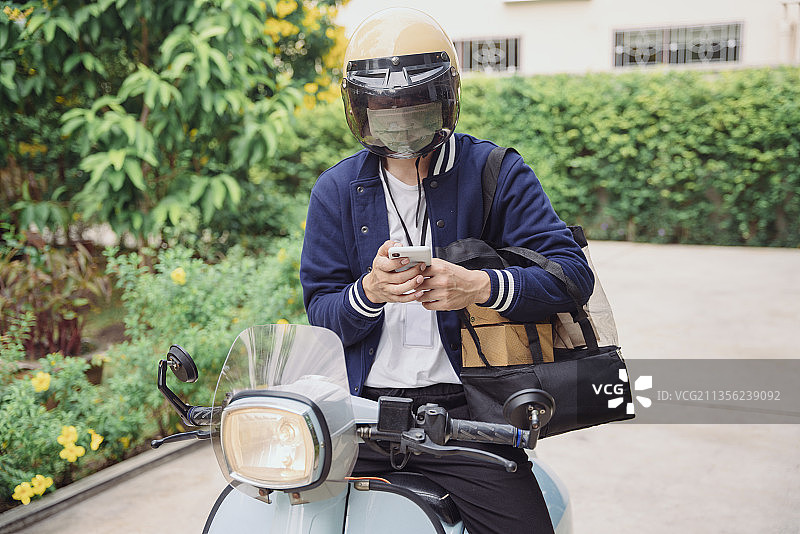摩托车送货员在应用智能手机上查看订单。图片素材