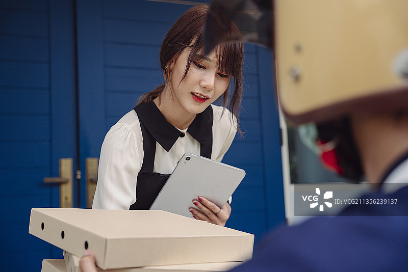 亚洲女人在笔记本电脑上用扫描程序代码检查订单和支付披萨费用。网上银行服务。食品交付。图片素材