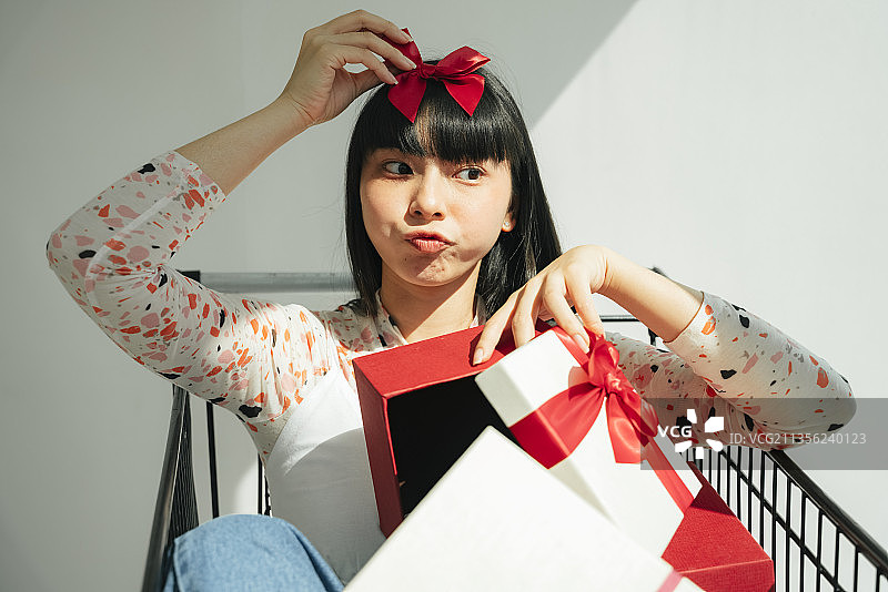 美丽的亚洲泰国长黑头发女人坐在购物车与许多礼物盒。装饰用的红丝带。图片素材