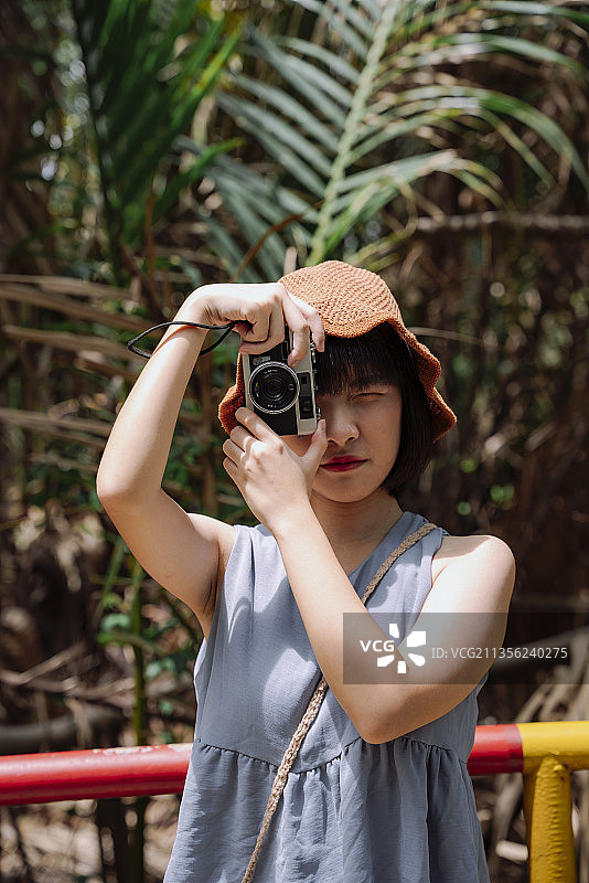 年轻的亚洲泰国妇女旅行者与古董相机在乡村小路。当地的旅行。图片素材