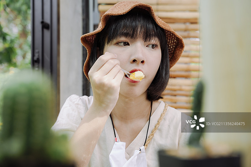 特写-美丽的亚洲泰国女人喜欢用勺子吃甜点蛋糕。当地的甜点。图片素材