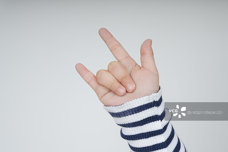 孩子手拿着“我爱你”的手势，隔着白色的背景。图片素材