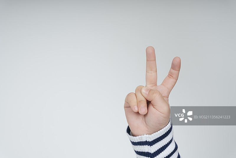 小孩手用胜利的两个手指手势孤立在白色背景上。图片素材