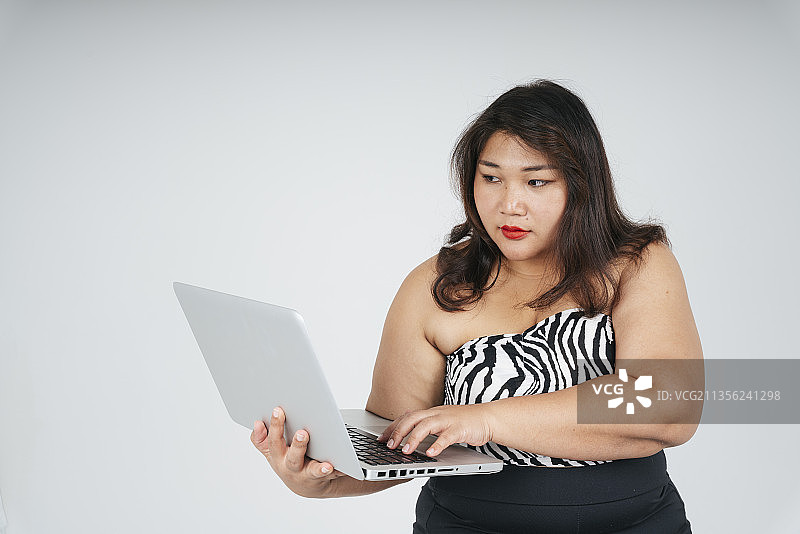 亚洲胖女商人的肖像使用电脑笔记本电脑在白色的背景。图片素材