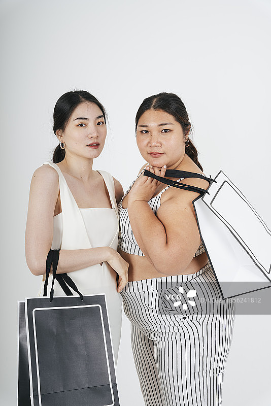 白色背景下，亚洲女人手牵着手一起逛街。图片素材