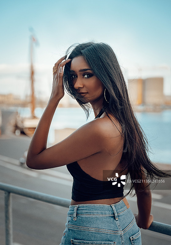 丹麦天空下栏杆旁的年轻女人肖像图片素材