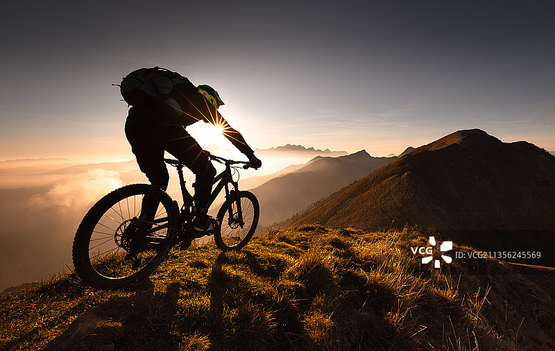 日落时分，男子在山上骑自行车图片素材