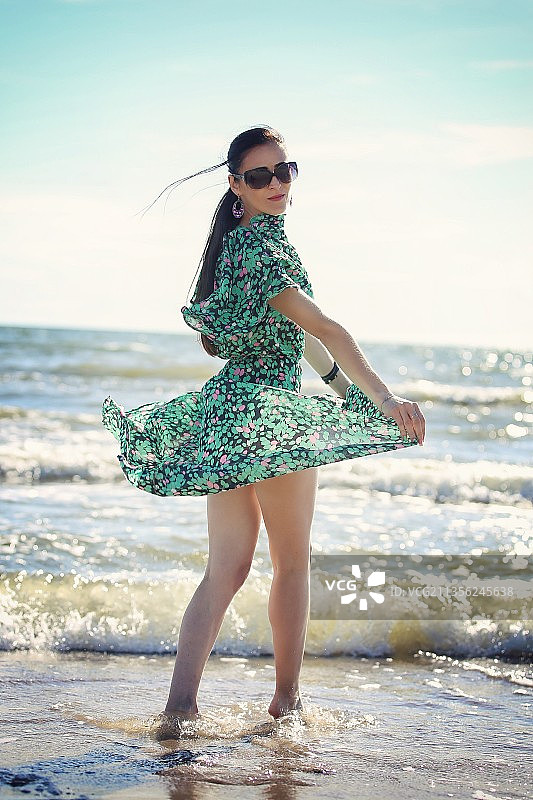 站在立陶宛海滩岸边的年轻女子全身照图片素材