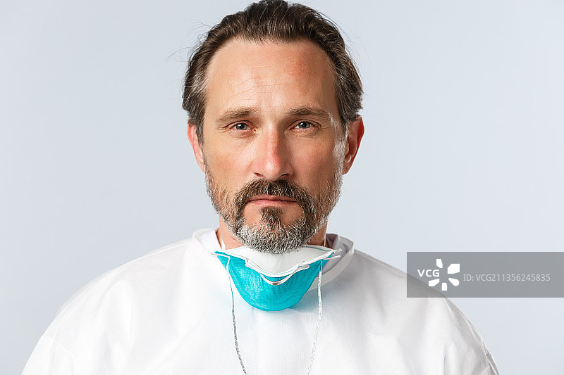 留着胡子的医生戴着口罩，以灰色背景为衬托的肖像图片素材