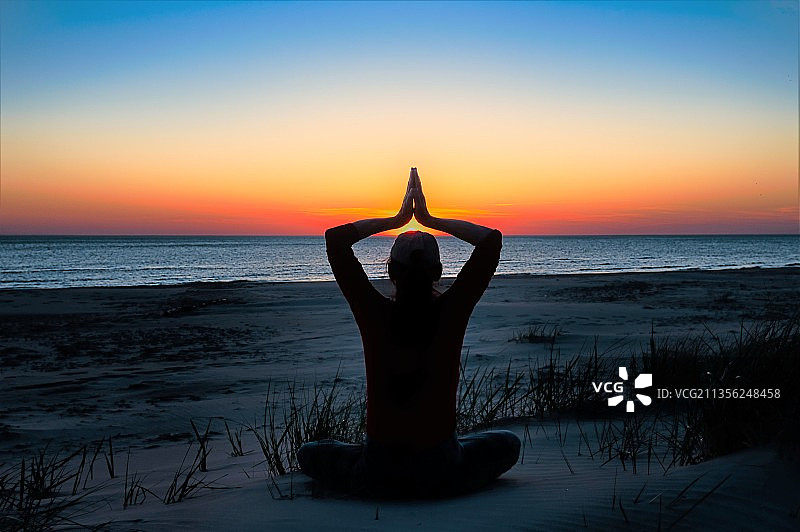 日落时在拉脱维亚海滩冥想的女人轮廓图片素材