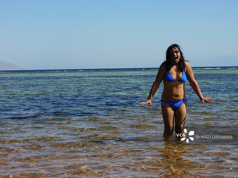 女人站在海边，背景是晴朗的天空图片素材