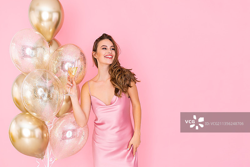 微笑的年轻女人拿气球粉色背景肖像图片素材