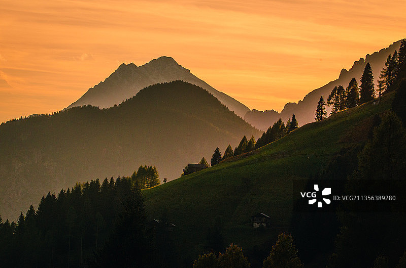 意大利贝卢诺省圣彼得罗迪卡多雷的橘色天空下的山脉剪影图片素材