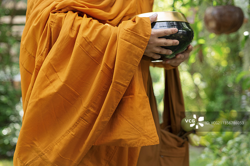一个和尚在公园里举着钵盂。图片素材