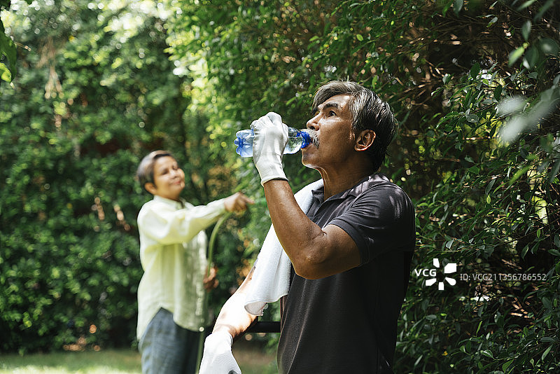 老人在花园工作后休息喝水。图片素材