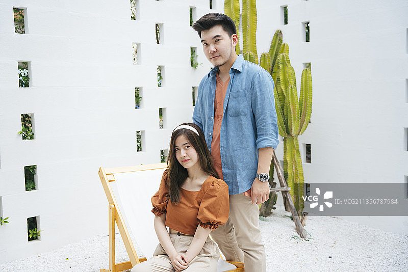 亚洲夫妇的时尚肖像与蓝色牛仔裤夹克和橙色衬衫在白色的背景。图片素材