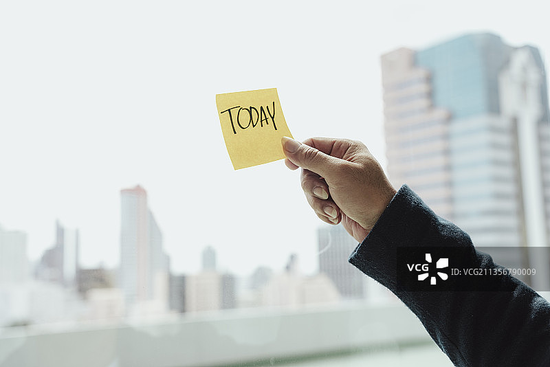 商人手拿便签纸贴在玻璃窗上。今天报价。图片素材