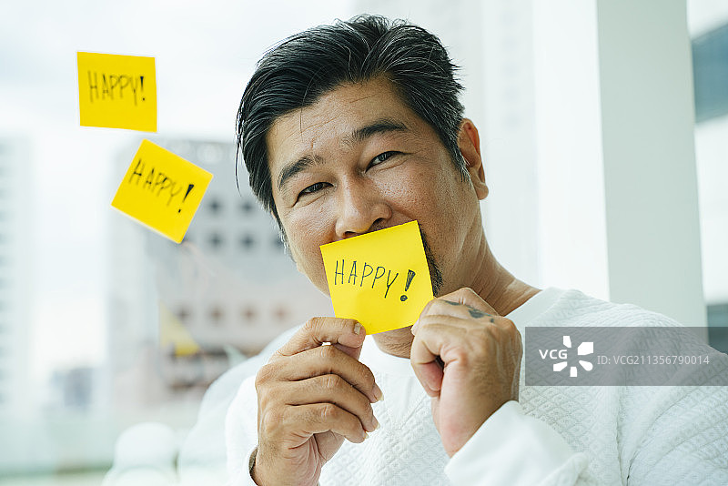 老人的特写肖像与黄色快乐的便利贴。图片素材