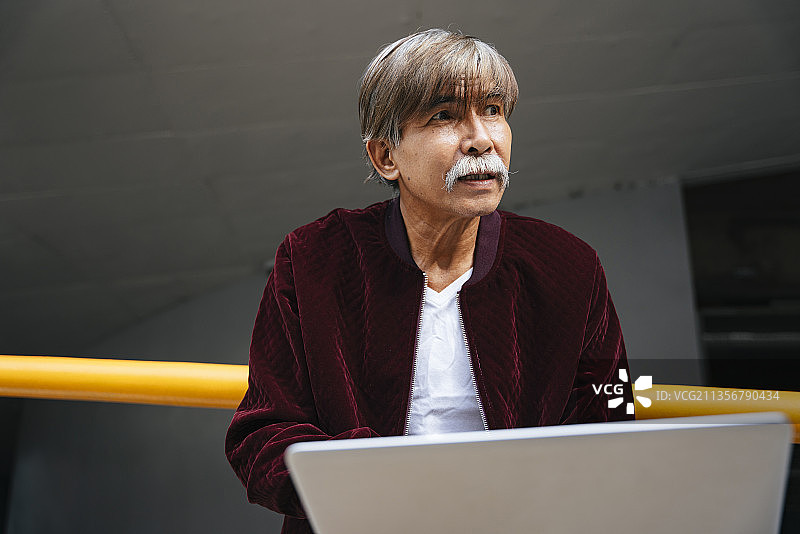 老年高级工程师的肖像与笔记本电脑户外工作。图片素材