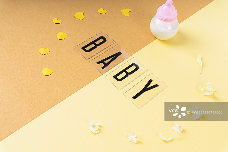 婴儿字与牛奶瓶在淡黄色和橙色的背景。图片素材