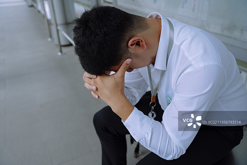 有压力的商人在公交车站等车时感到又累又累。图片素材