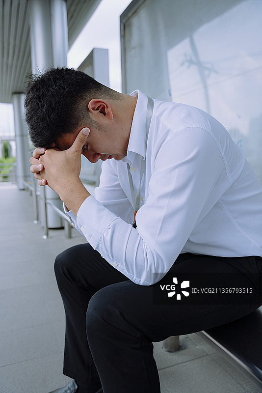 有压力的商人在公交车站等车时感到又累又累。图片素材