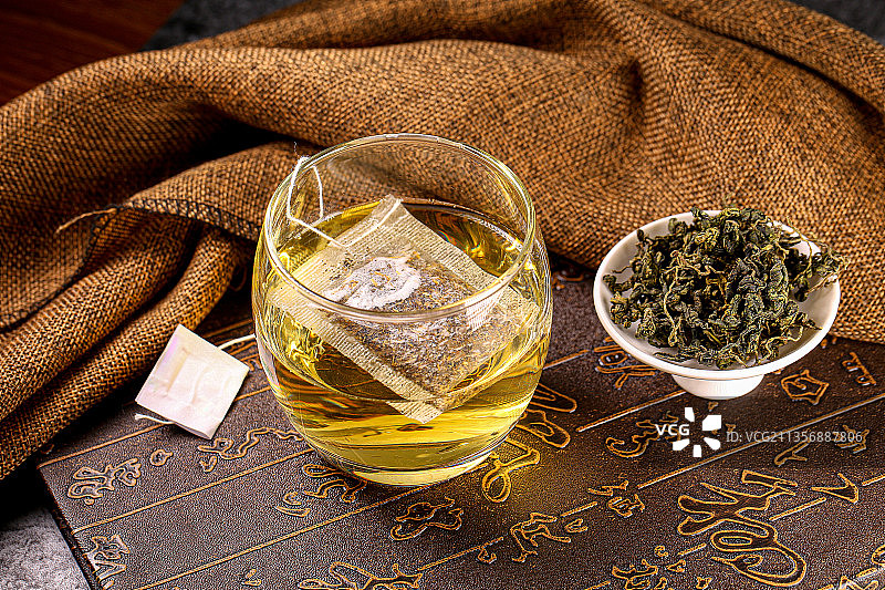 汤色金黄的绞股蓝袋泡茶和原料碟子图片素材